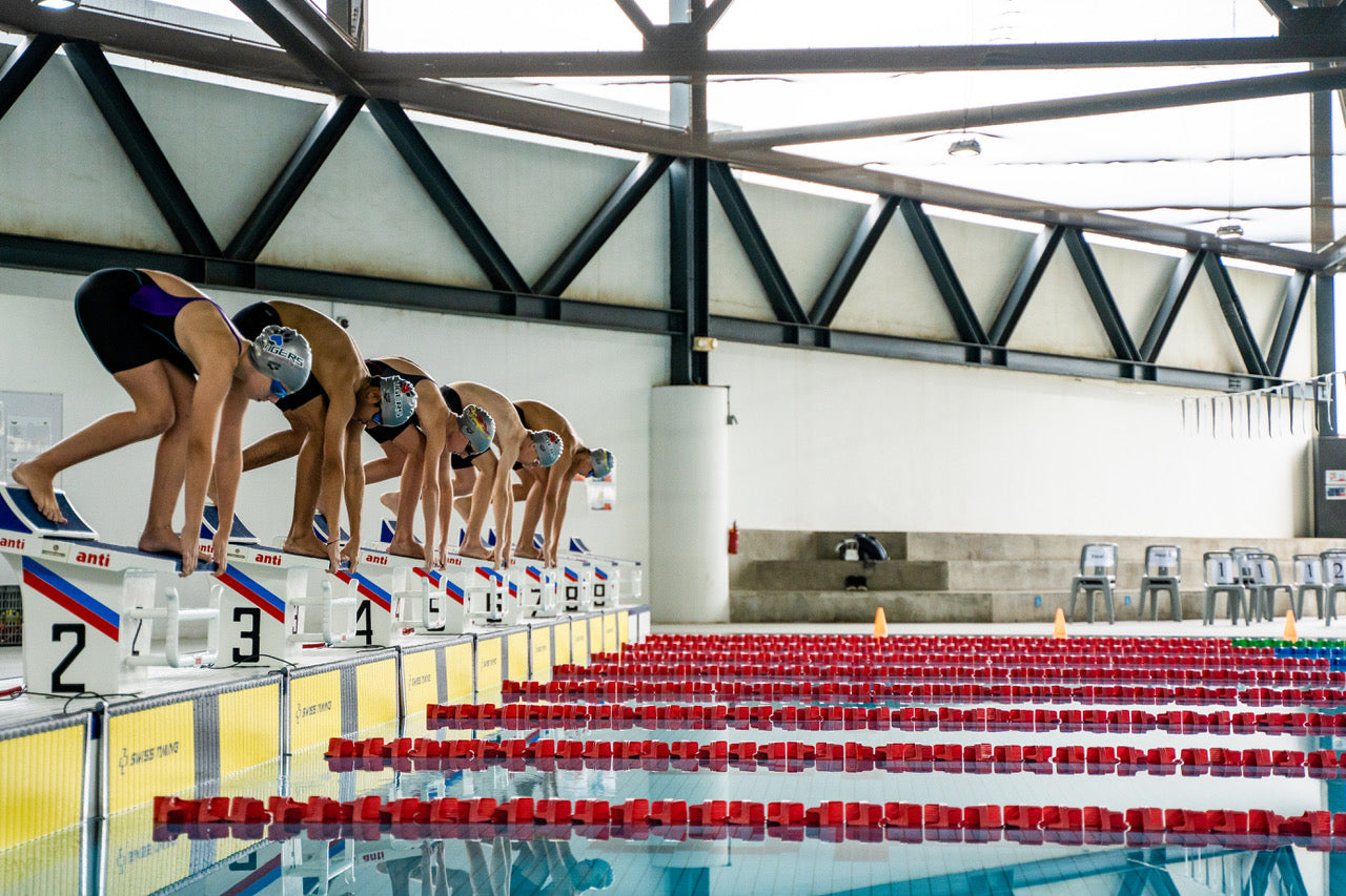 Indoor Olympic competition swimming pool with starting blocks and lane reflections